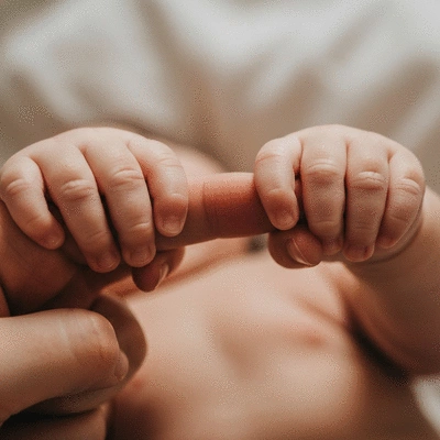 Close-up of baby twin hands holding onto a parent's finger