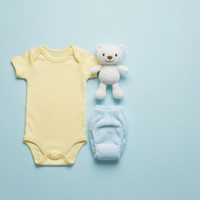 Minimalist flat lay of baby clothes, diapers, and a small toy on a light background, symbolizing preparation